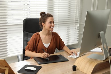 Professional retoucher working on graphic tablet at desk in office