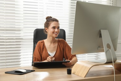 Professional retoucher working on graphic tablet at desk in office