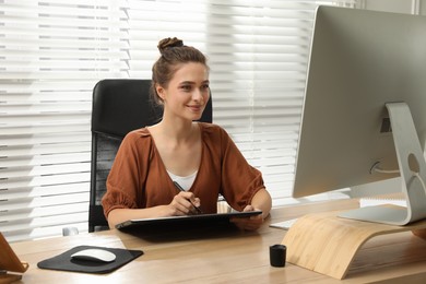 Professional retoucher working on graphic tablet at desk in office