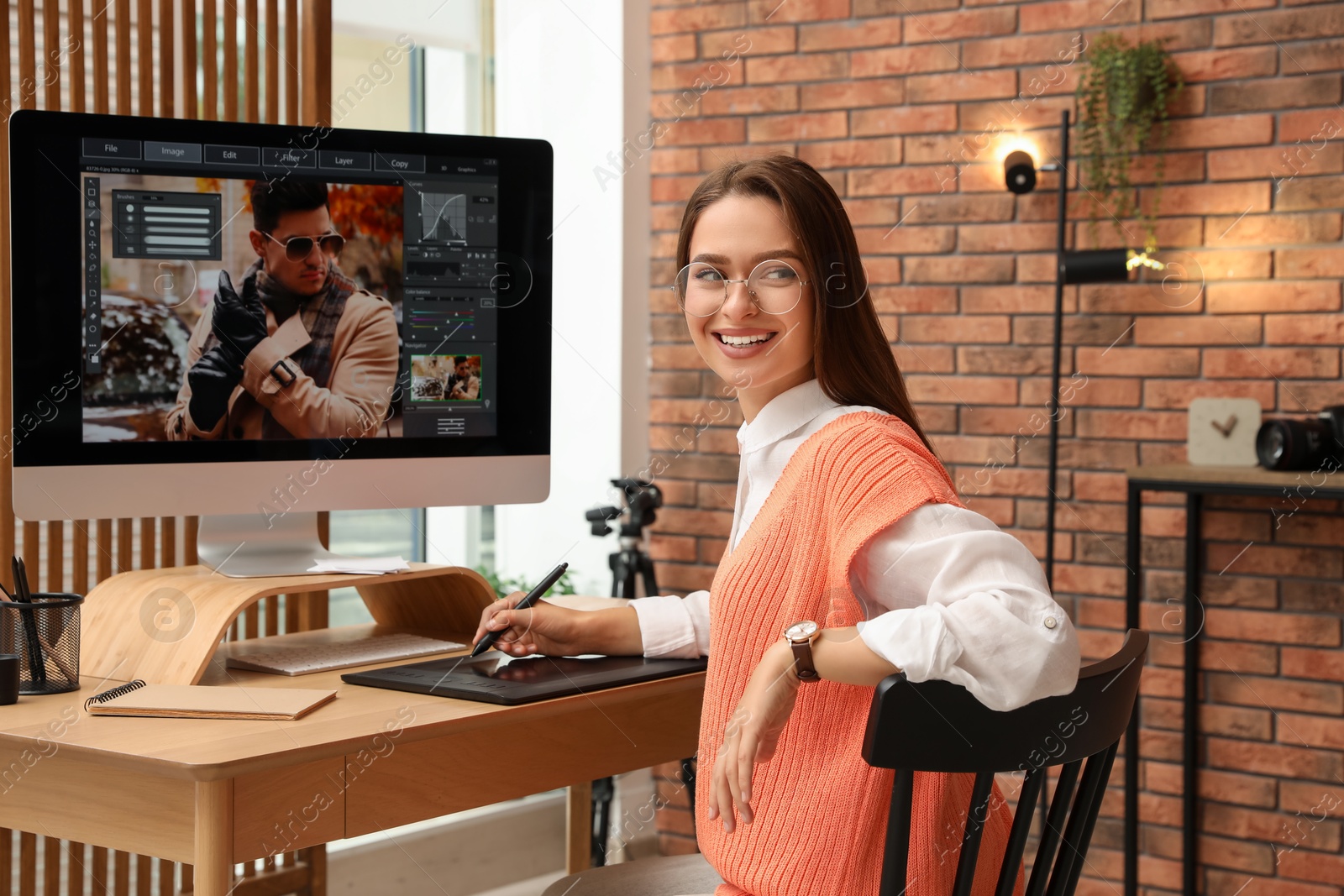 Photo of Professional retoucher working on graphic tablet at desk in office