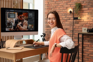 Professional retoucher working on graphic tablet at desk in office