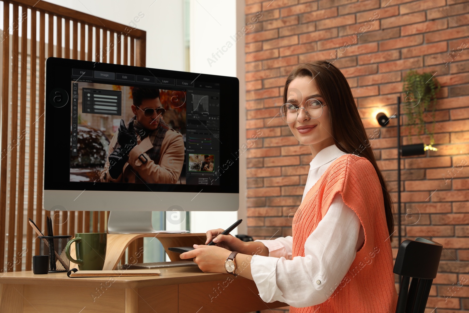 Photo of Professional retoucher working on graphic tablet at desk in office