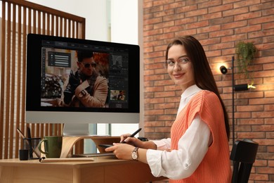 Professional retoucher working on graphic tablet at desk in office