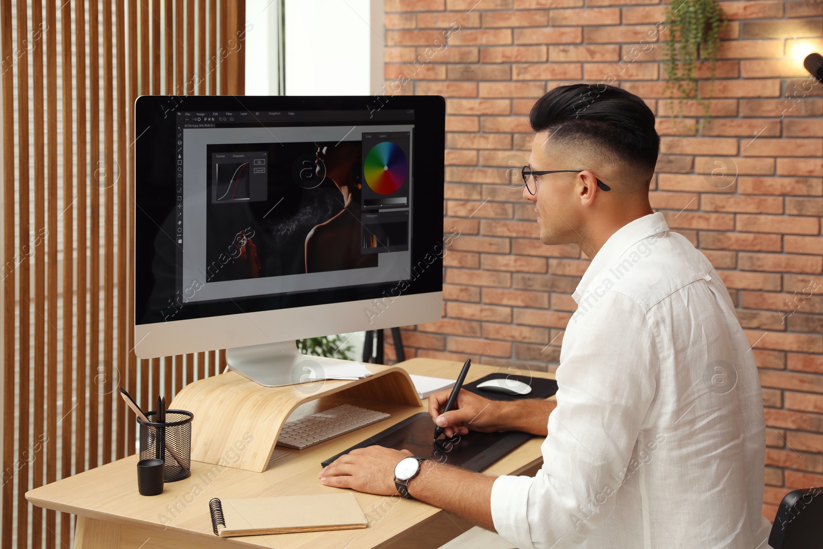 Photo of Professional retoucher working on graphic tablet at desk in office