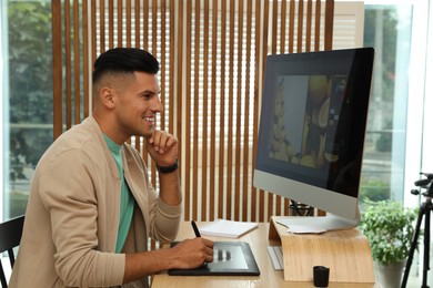 Photo of Professional retoucher working on graphic tablet at desk in office