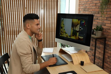 Professional retoucher working on graphic tablet at desk in office