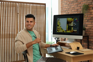 Professional retoucher working on graphic tablet at desk in office