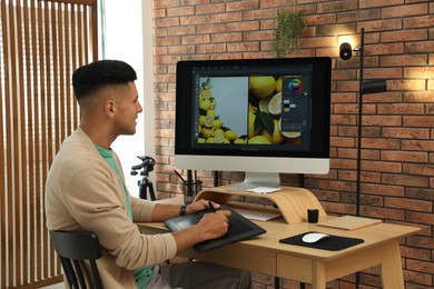 Photo of Professional retoucher working on graphic tablet at desk in office