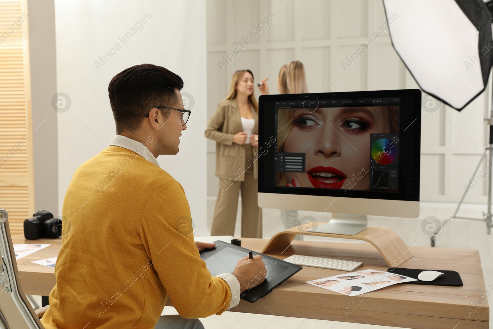 Photo of Professional retoucher working with graphic tablet at desk in photo studio