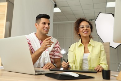 Professional retoucher with colleague working at desk in photo studio