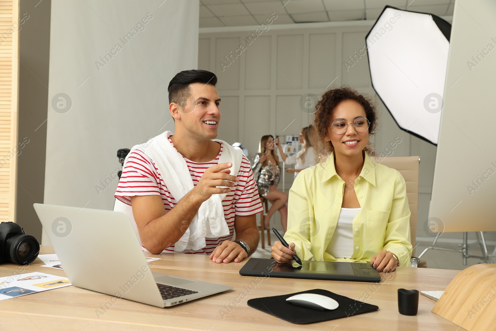 Photo of Professional retoucher with colleague working at desk in photo studio