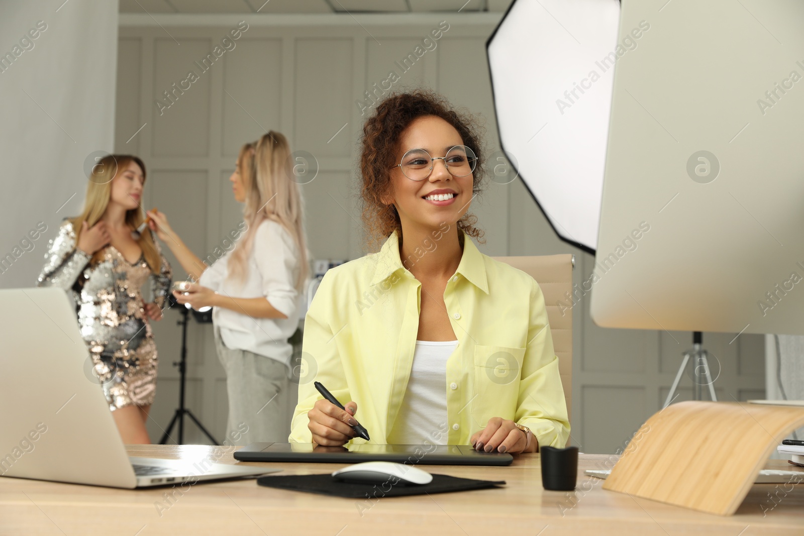 Photo of Professional African American retoucher working with graphic tablet at desk in photo studio