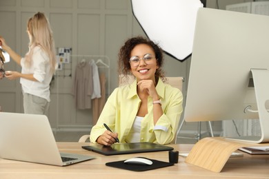 Professional African American retoucher working with graphic tablet at desk in photo studio