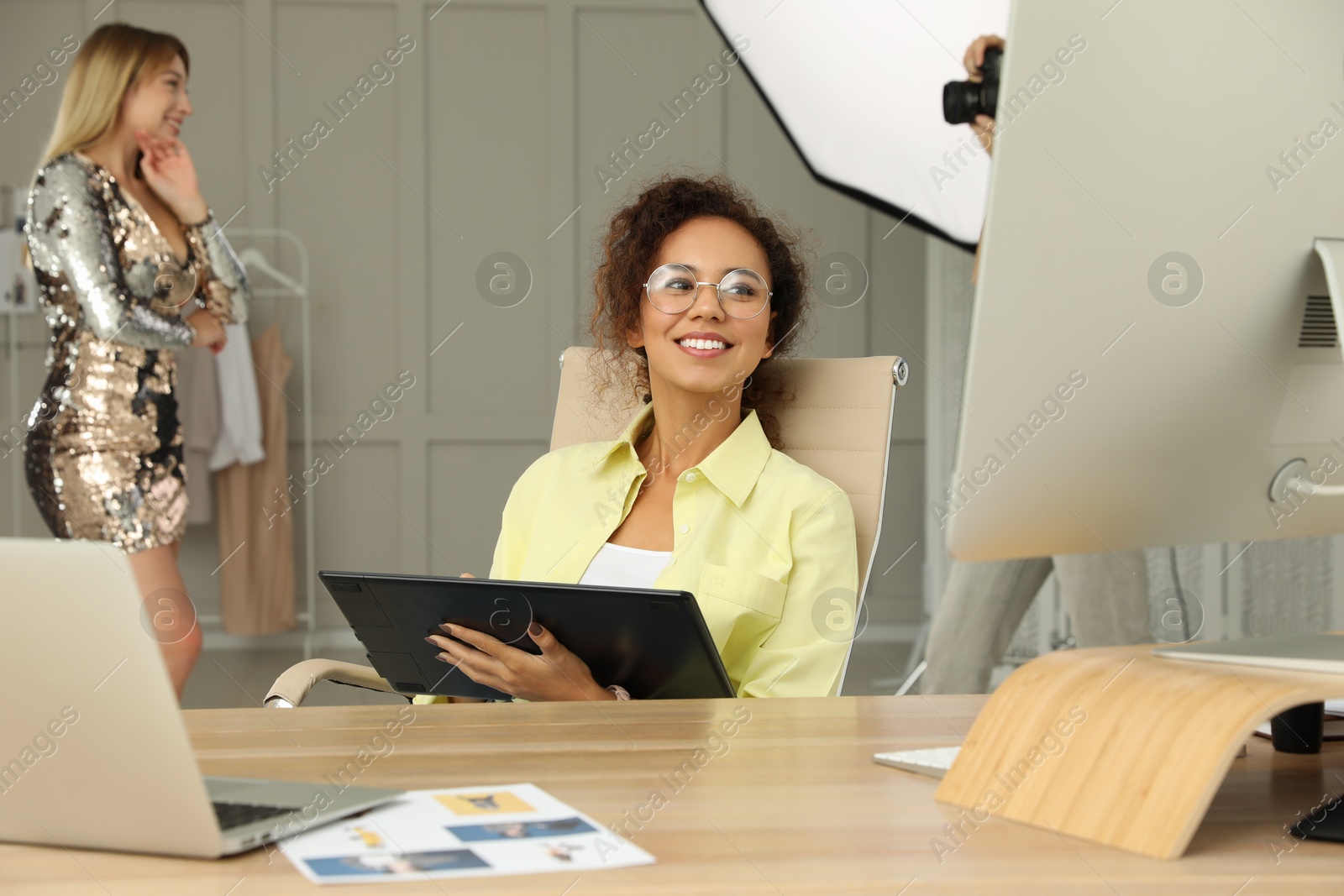 Photo of Professional African American retoucher working with graphic tablet at desk in photo studio