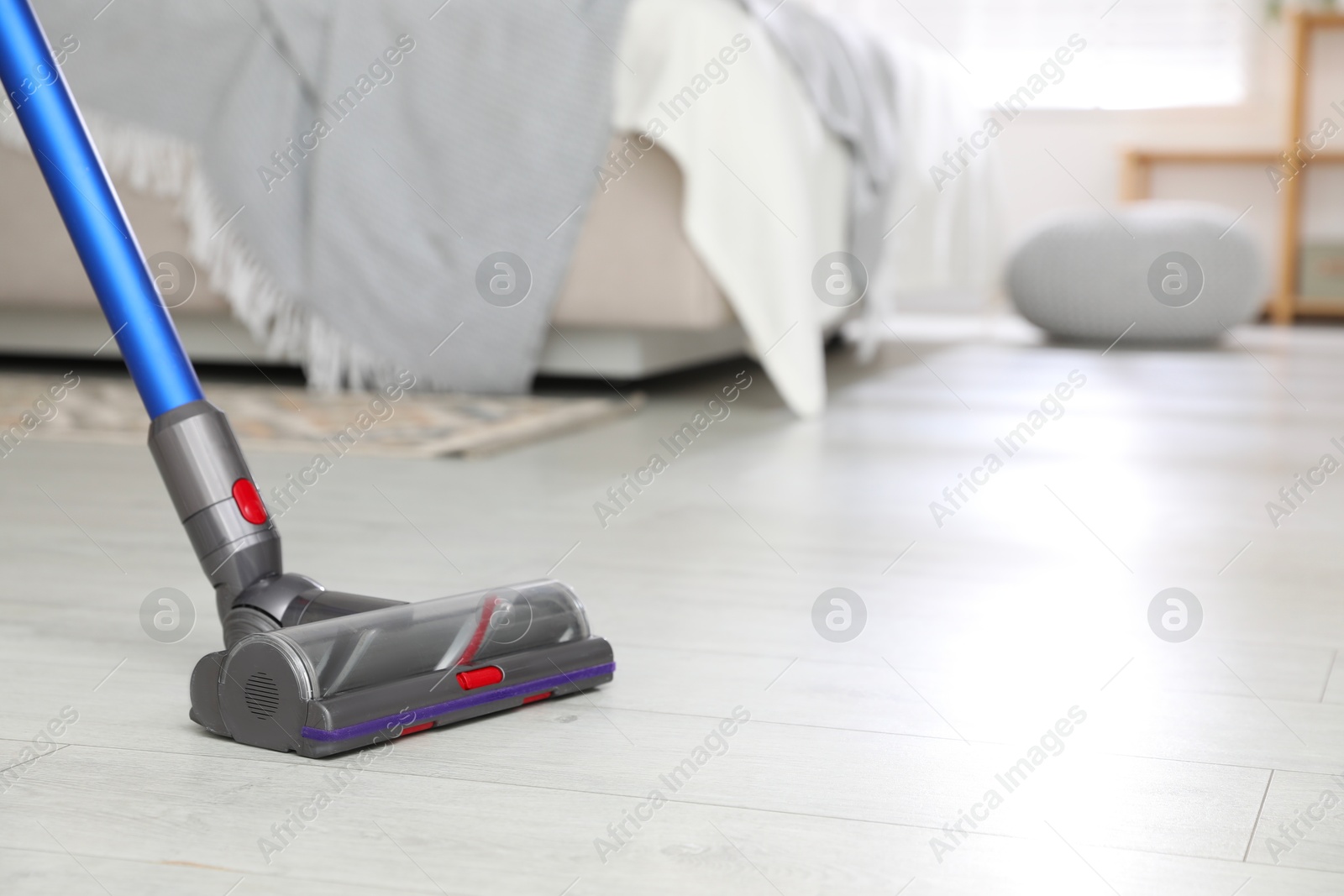 Photo of Cleaning floor with cordless vacuum cleaner indoors, closeup. Space for text