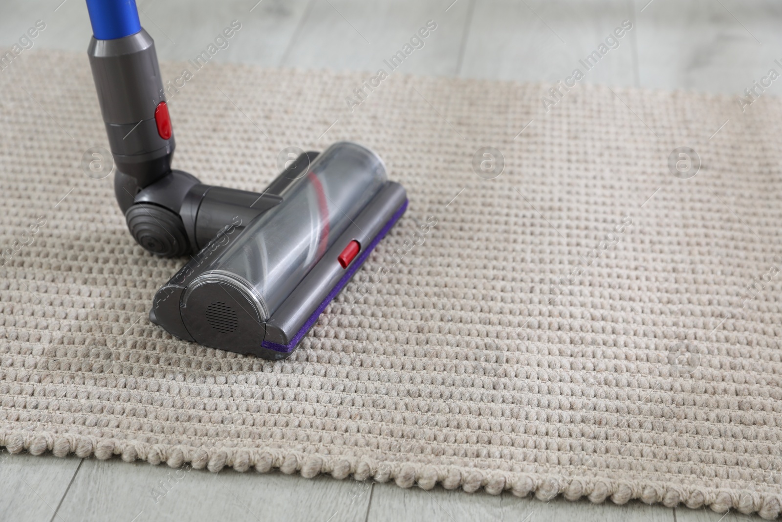 Photo of Cleaning carpet with cordless vacuum cleaner indoors, closeup. Space for text