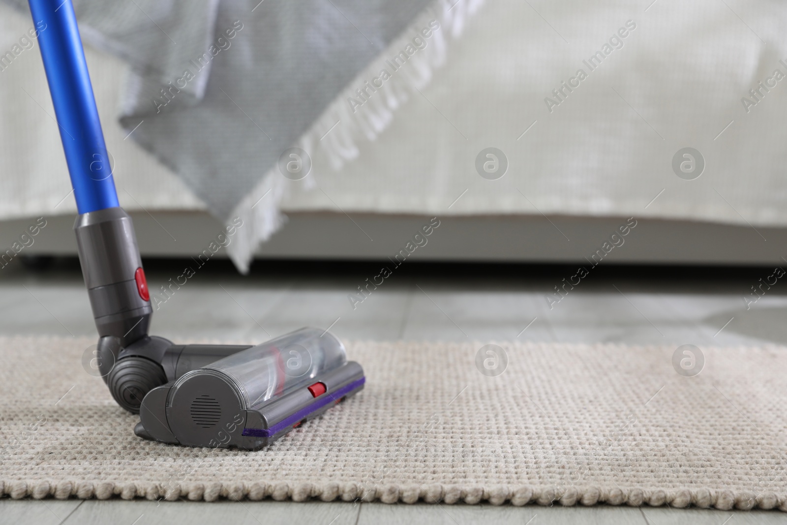 Photo of Cleaning carpet with cordless vacuum cleaner indoors, closeup. Space for text