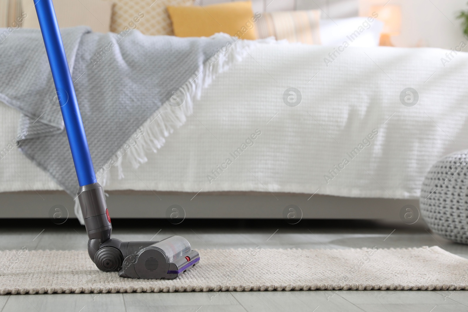 Photo of Cleaning carpet with cordless vacuum cleaner indoors, closeup. Space for text