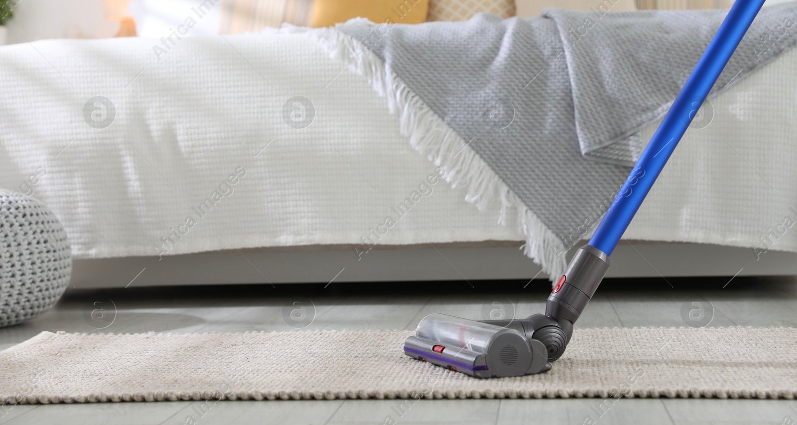 Photo of Cleaning carpet with cordless vacuum cleaner indoors, closeup. Space for text