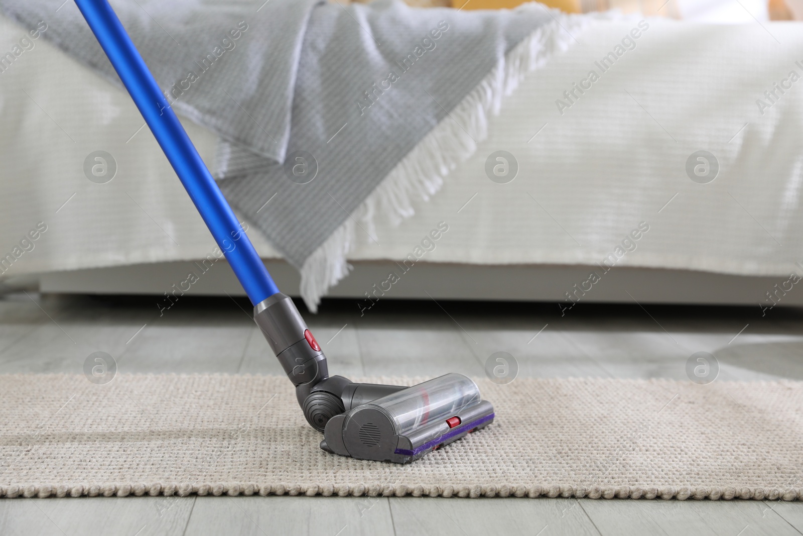 Photo of Cleaning carpet with cordless vacuum cleaner indoors, closeup. Space for text