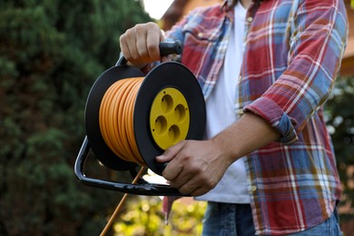 Photo of Man with extension cord reel outdoors, closeup