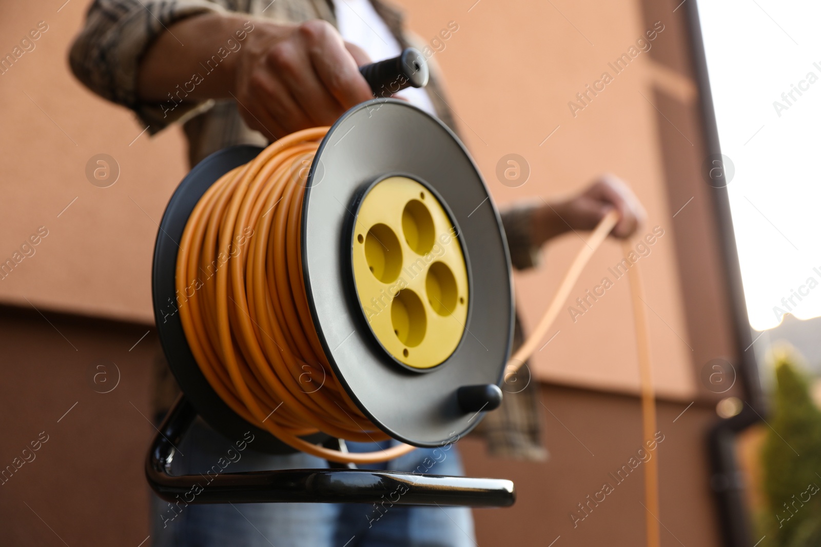 Photo of Man with extension cord reel outdoors, closeup