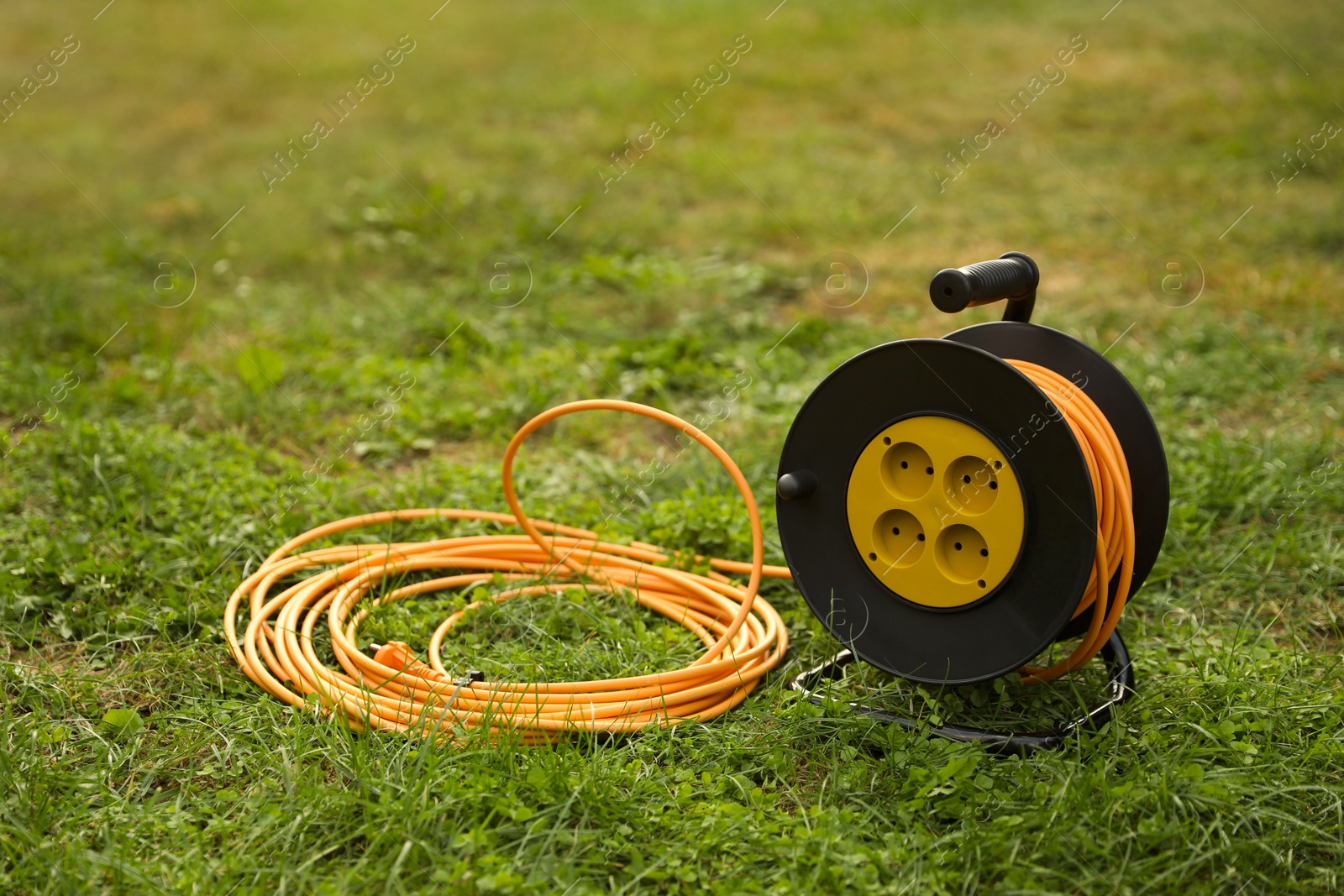 Photo of Extension cord reel on green grass outdoors