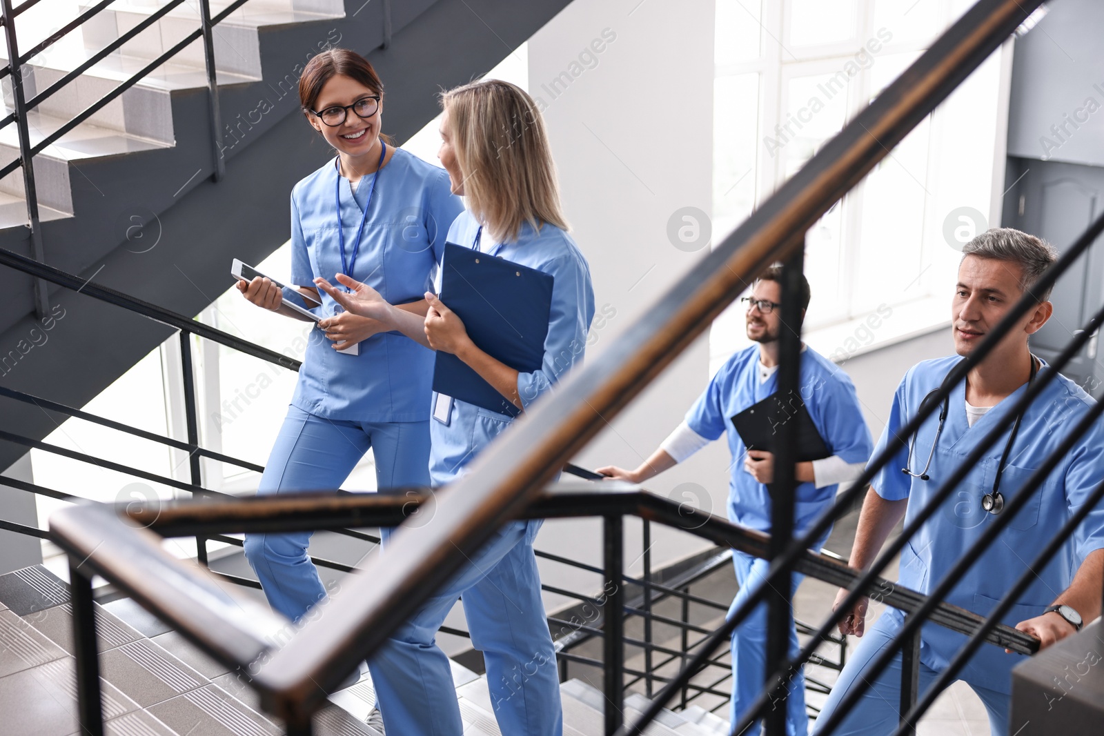 Photo of Healthcare workers with tablet and clipboard walking up stairs in hospital