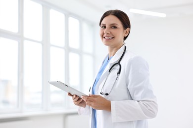 Smiling healthcare worker with tablet in hospital