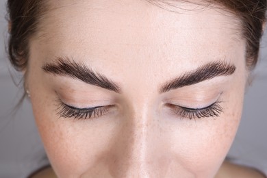 Photo of Woman after brow lamination procedure on grey background, closeup