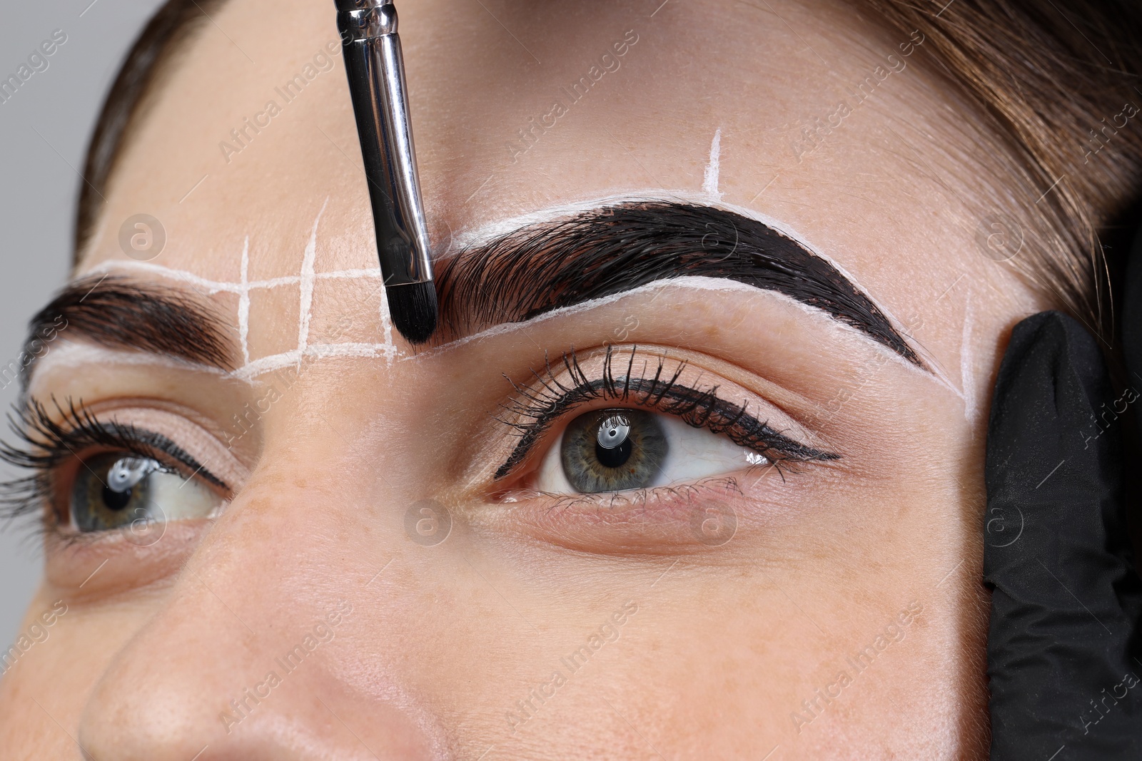 Photo of Young woman undergoing henna eyebrows dyeing procedure, closeup