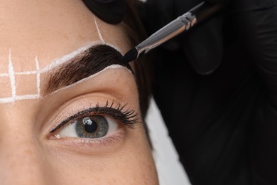 Photo of Young woman undergoing henna eyebrows dyeing procedure, closeup