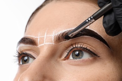 Young woman undergoing henna eyebrows dyeing on light background, closeup