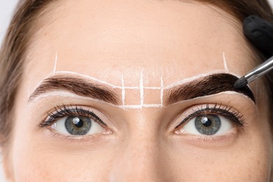 Photo of Young woman undergoing henna eyebrows dyeing procedure, closeup