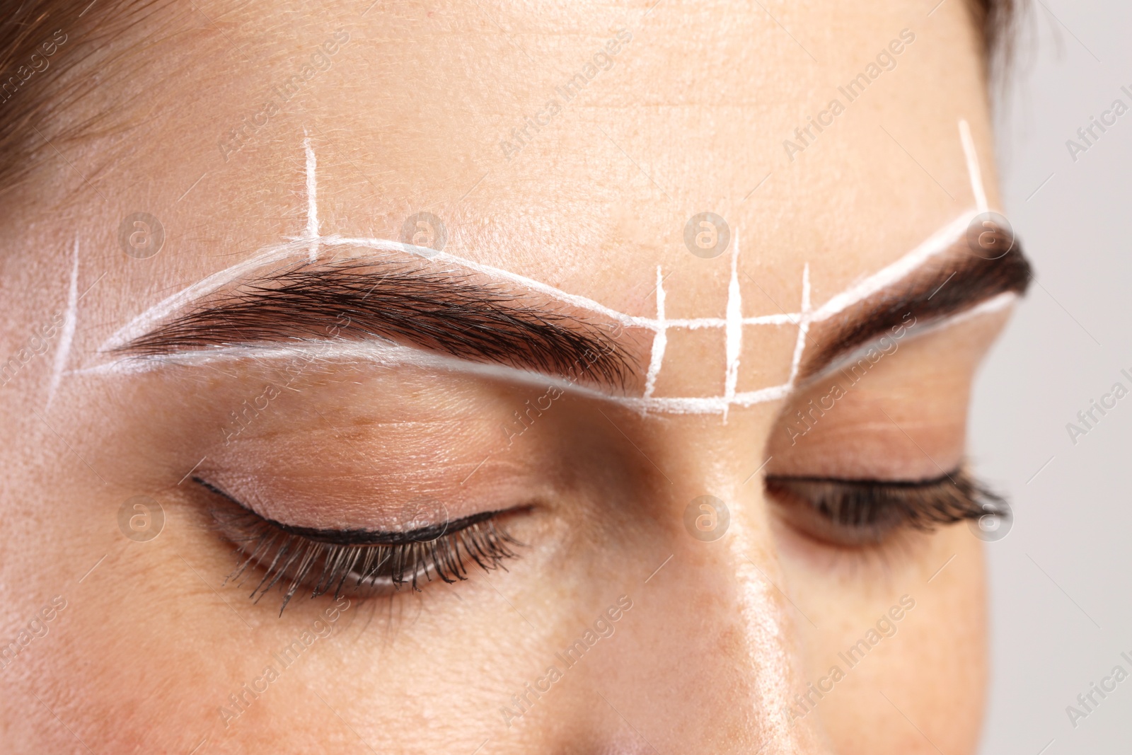 Photo of Young woman during henna eyebrows dyeing procedure on light background, closeup