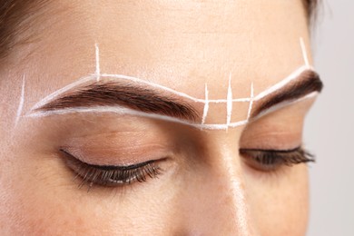 Young woman during henna eyebrows dyeing procedure on light background, closeup