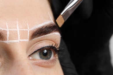 Photo of Young woman undergoing henna eyebrows dyeing procedure, closeup