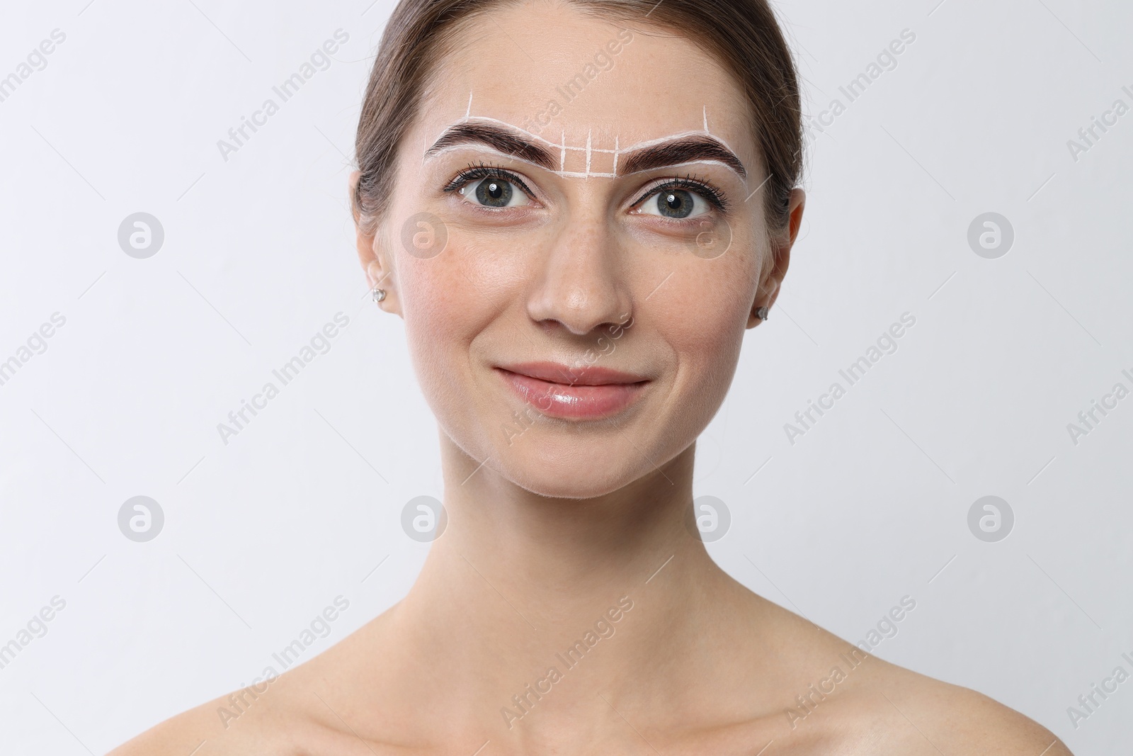 Photo of Beautiful young woman during henna eyebrows dyeing procedure on light background, closeup