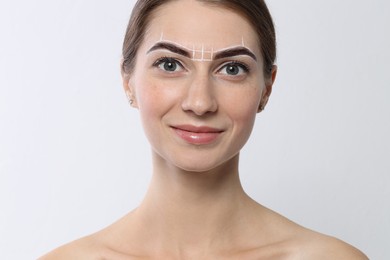 Photo of Beautiful young woman during henna eyebrows dyeing procedure on light background, closeup