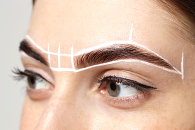 Young woman during henna eyebrows dyeing procedure on white background, closeup