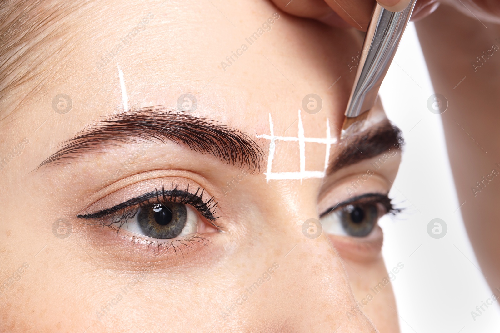 Photo of Young woman undergoing henna eyebrows dyeing procedure, closeup