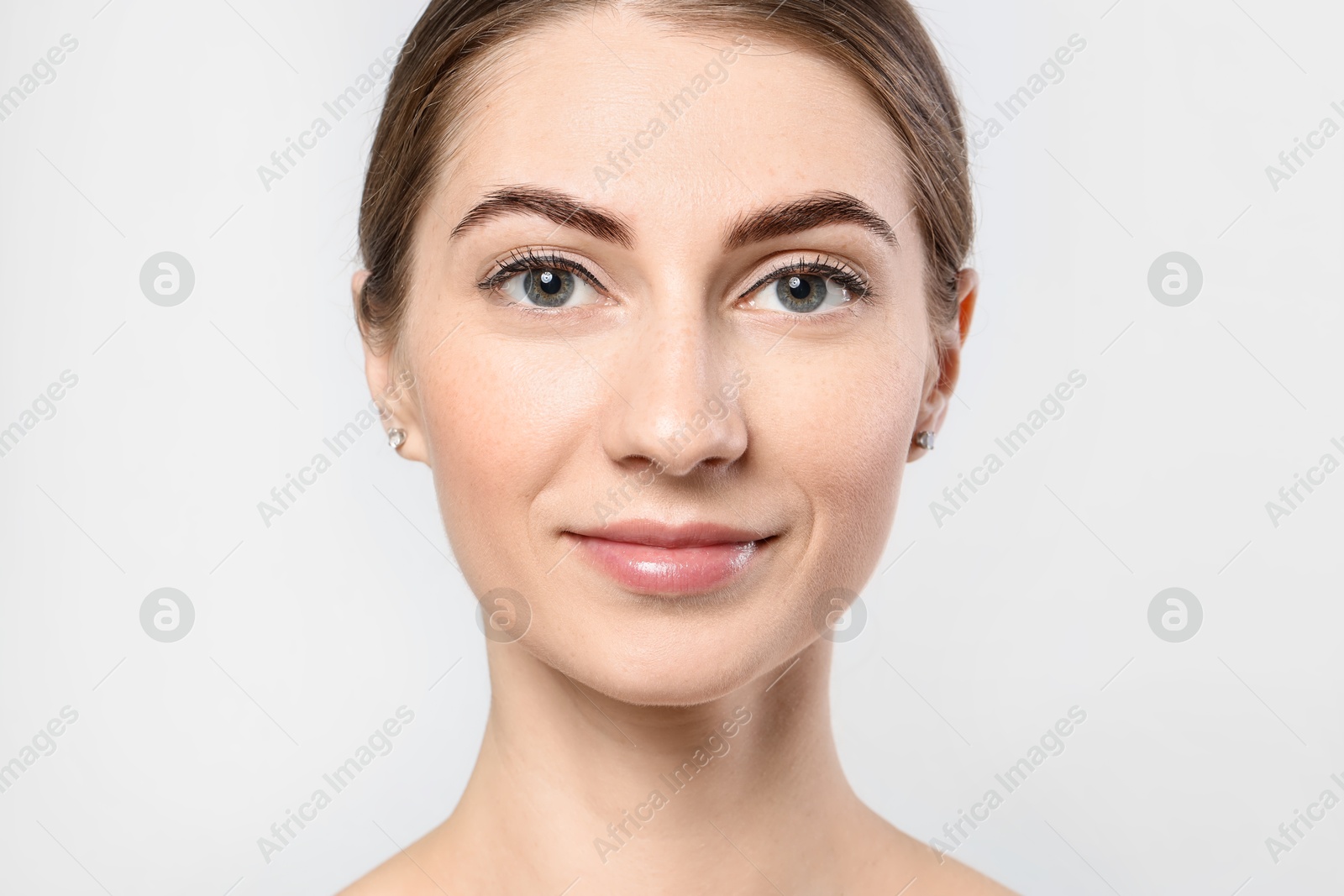 Photo of Beautiful young woman after henna eyebrows dyeing on light background, closeup