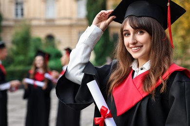 Happy students with diplomas after graduation ceremony outdoors, selective focus