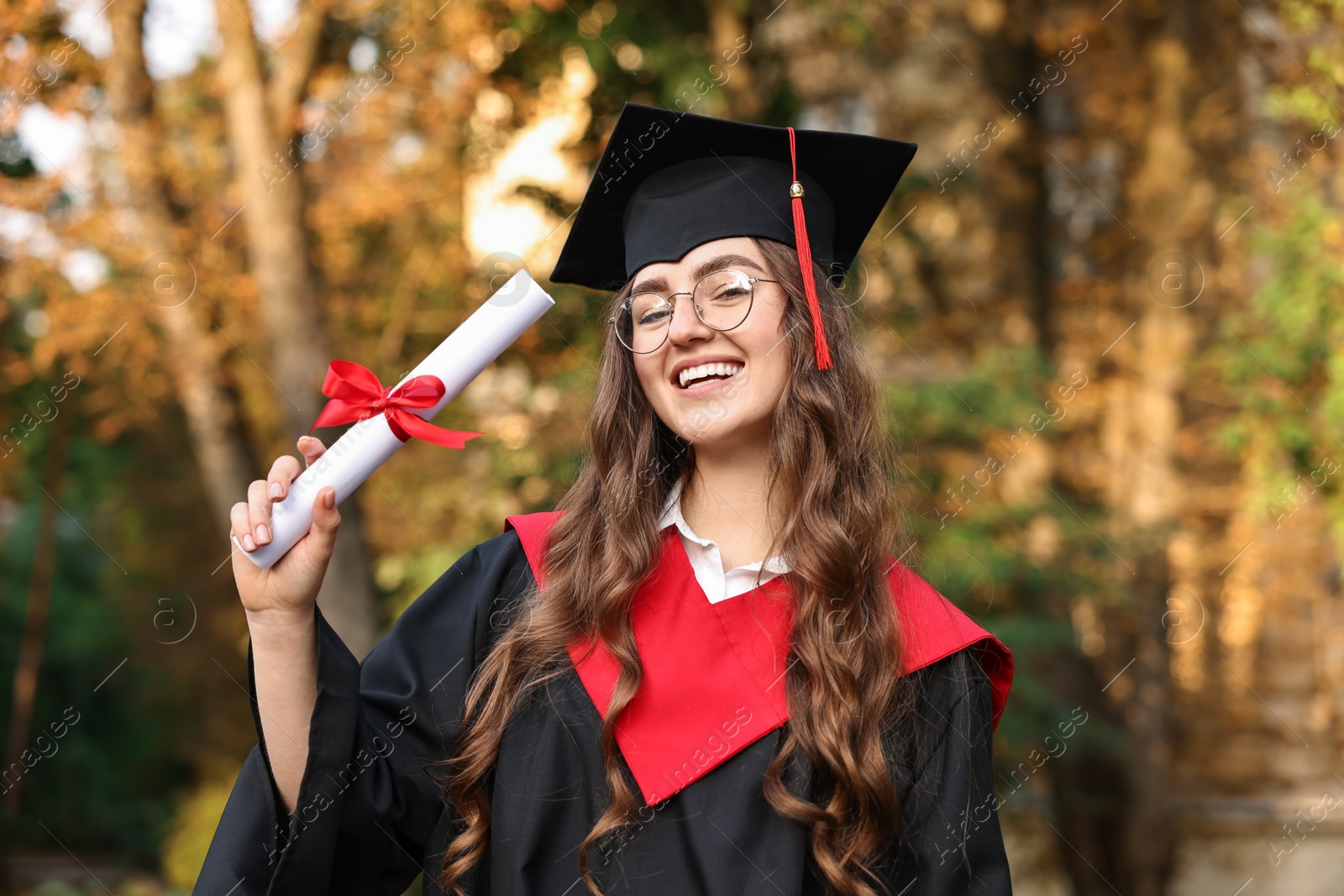 Photo of Happy student with diploma after graduation ceremony outdoors