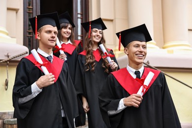 Photo of Graduation ceremony. Happy students with diplomas outdoors, selective focus