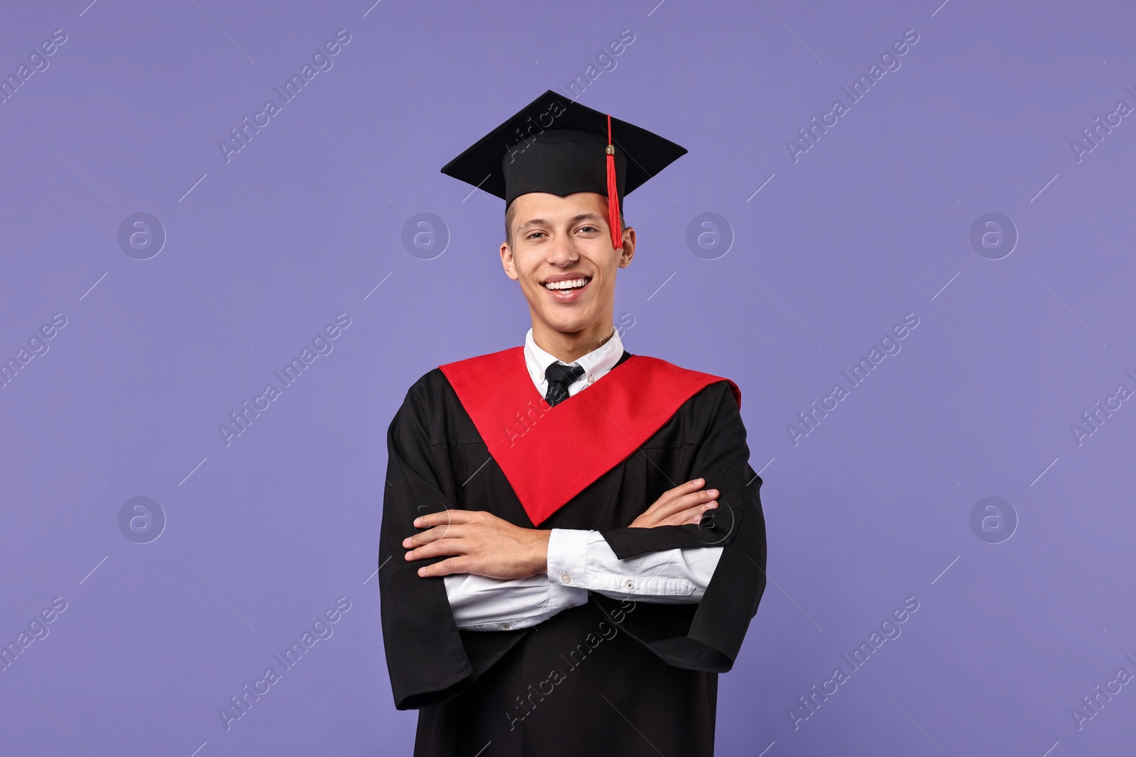 Photo of Happy student with crossed arms after graduation on violet background