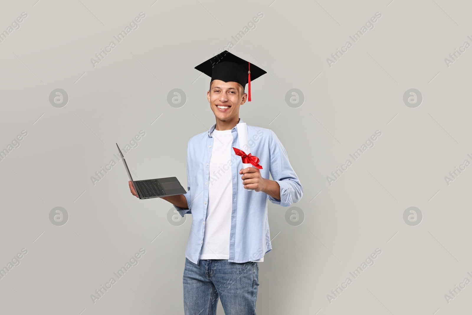 Photo of Happy student with diploma and laptop after graduation on grey background