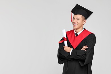 Photo of Happy student with diploma after graduation on light grey background. Space for text