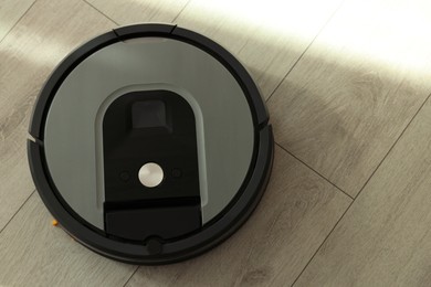 One robotic vacuum cleaner on wooden floor, top view