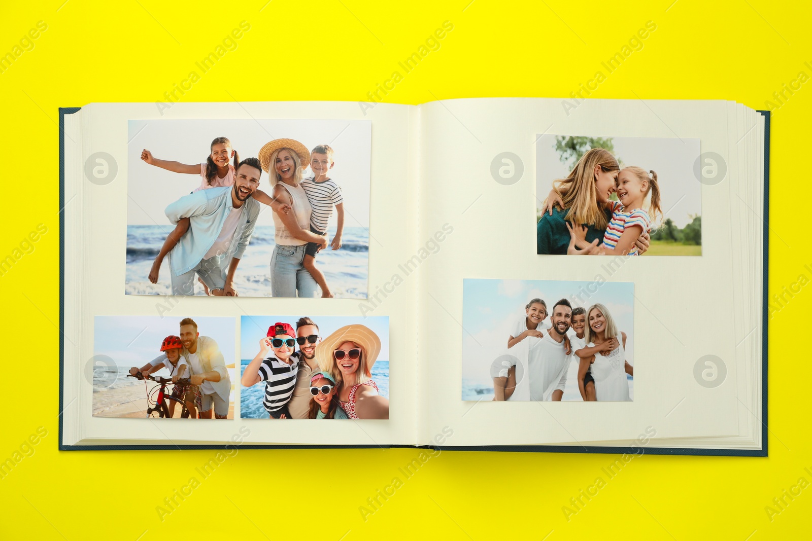 Photo of Open photo album with different photos on yellow background, top view